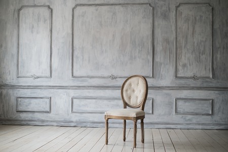 Antique white chair over luxury white wall design bas-relief stucco mouldings roccoco elements.の写真素材