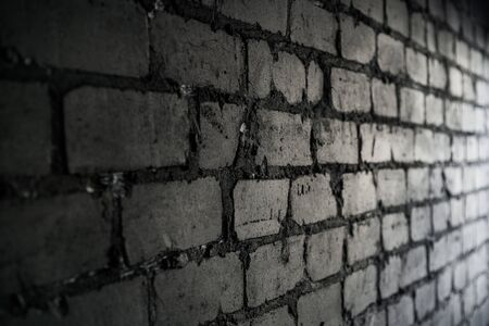 Side view on black brick wall lit by light from the window.の写真素材