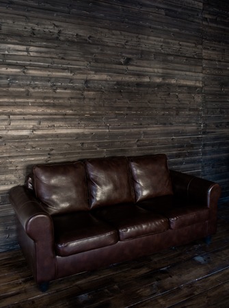 vintage brown leather sofa on a wooden wall and floor.の写真素材