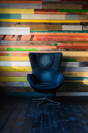 Modern egg chair on a colorful wooden wall.の写真素材