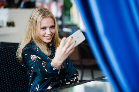 Portrait of a smiling pretty blonde talking a selfieの写真素材