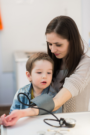 Attractive woman and her kid with a blood pressure meter tonometer.の写真素材