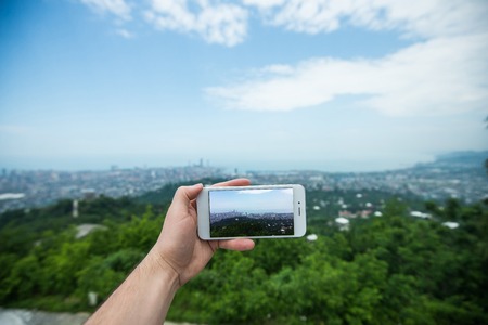 Hand with smartphone taken pictures of city landscape.の写真素材