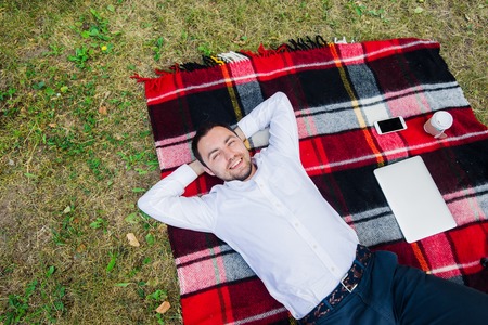 Happy young man with laptop relaxing on the grass, view from the top.の写真素材