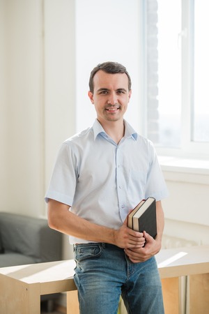 Closeup portrait, young business man or teacher in blue shirt reading, perusing books at school library class.の写真素材