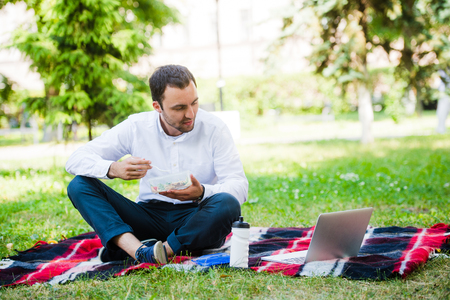 Young and attractive man relaxes in the park at lunch time.の写真素材