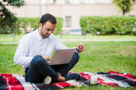A man is working using laptop at park. Outdoor, guy look challenged and thinking.の写真素材