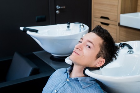 Profile view of a young man getting ready for his hair washed .の写真素材