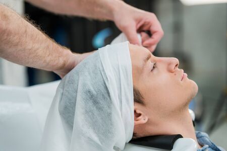 Hairstylist washing client's hair in barber shop.の写真素材