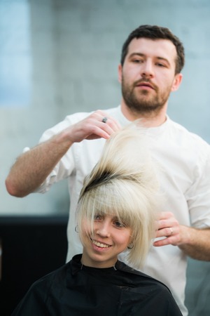 male hairdresser puts woman's hair in a hairdressing salon.の写真素材