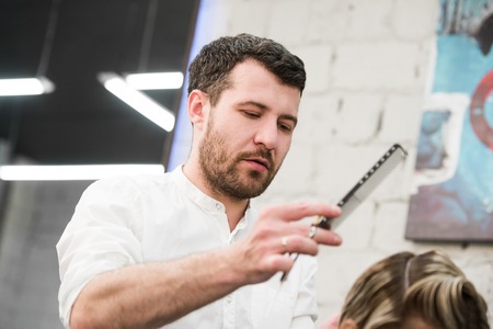 male hairdresser puts woman's hair in a hairdressing salon.