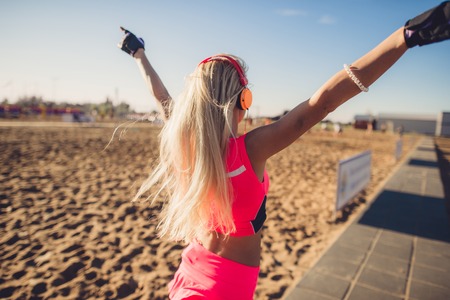 Success fitness woman concept with sports armband and earphones. Winning concept of female athlete runner cheering with arms raised up for achievement in weight loss or life goalの写真素材