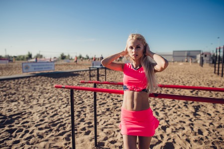 Beautiful fitness athlete woman resting after work out exercising on beach summer evening in sunny sunshine outdoor portraitの写真素材