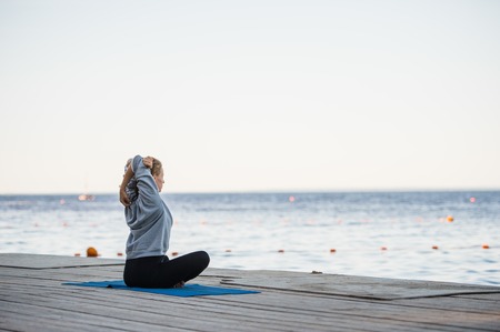 An image of a pretty woman doing yoga at the lake.の写真素材
