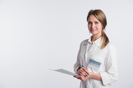 Beautiful nurse smiling and taking notes on a white isolated background.の写真素材