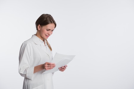 Portrait of cheerful female doctor with documents, isolated over white background.の写真素材