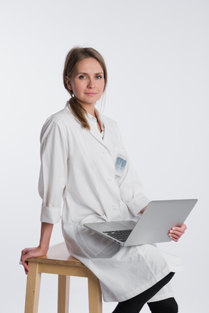 Smiling female doctor working on her laptop against a white background.の写真素材