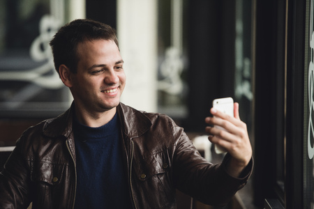Young man taking a selfie in coffee shop.