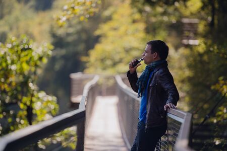 Young man with custom box mode vape device vaping an electronic cigarette outdoor at beautiful place outdoors.の写真素材