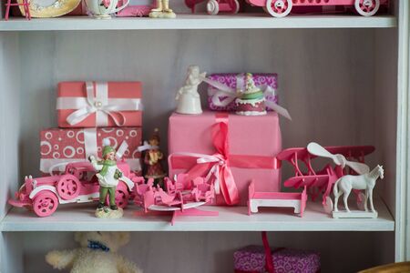 Christmas gifts in box on a shelf, pink car, airplane, wooden horse and gingle bellの写真素材