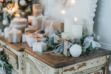 Christmas decoration on ancient vintage old commode chest of drawers. Hand made craft gifts, candels and a tree at background. Selective focus.の写真素材