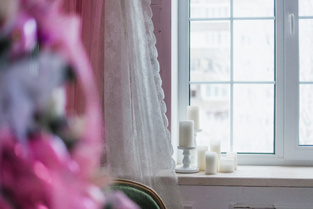 Candles near the window and blured Christmas tree on a foreground.の写真素材