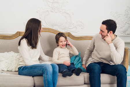 family phone talking - cute little boy and his mother are sitting on the sofa and talking by cell phoneの写真素材