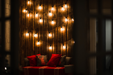 Wooden room in rustic house with wooden wall and designer light bulbs, decorated place for seat. Red gray pillowsの写真素材
