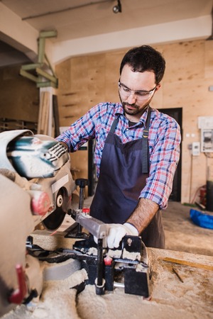 Carpenter Using Circular Saw for wood at his workshop.の写真素材
