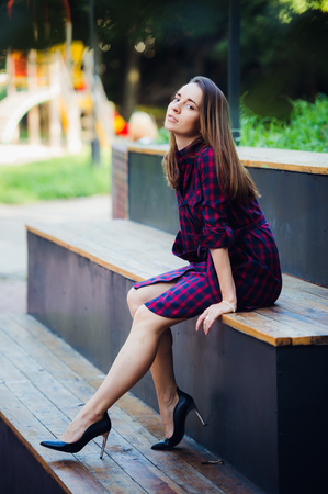 Girl wearing checkered dress sitting down at skatepark looking at cameraの写真素材