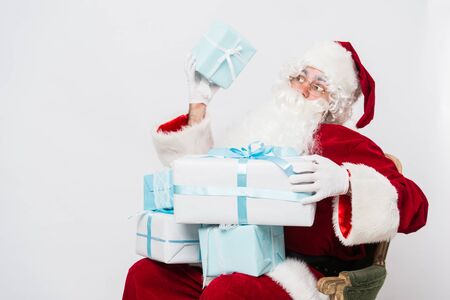 Photo of happy Santa Claus with giftboxes looking at them.の写真素材