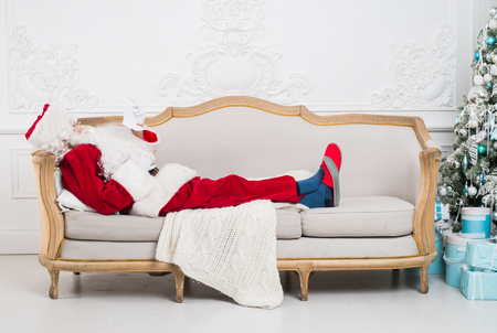 Santa claus using mobile phone at home during christmas time.の写真素材