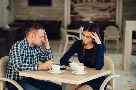 Young couple arguing in a cafe. She's had enough, boyfriend is apologizing. Relationship problemsの写真素材