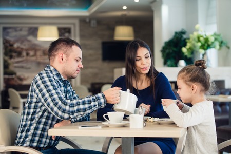 Happy family Enjoying tea In Cafe Together.