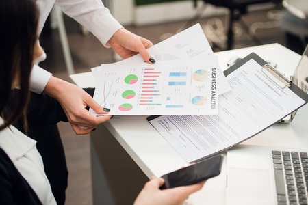 Business team analyzing income charts and graphs with modern laptop computer and using smart phone. Top view close up. Business analysis and strategy concept.の写真素材