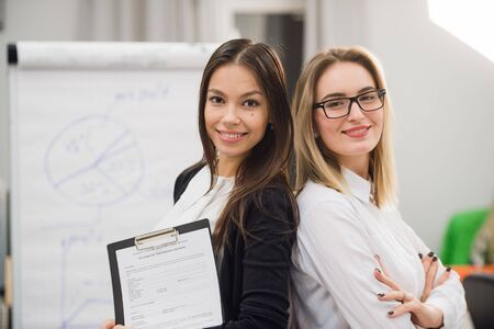 two business women standing at office in front of flip chart.の写真素材