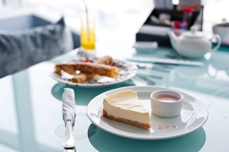 Slice of cheesecake on white plate and glass table in cafe.の写真素材