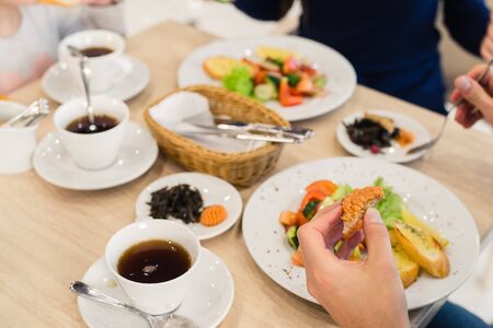 Close Up Of Family Sitting At Table Enjoying Meal At Home