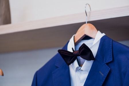 Close-up of blue jacket with bow tie on a hanger