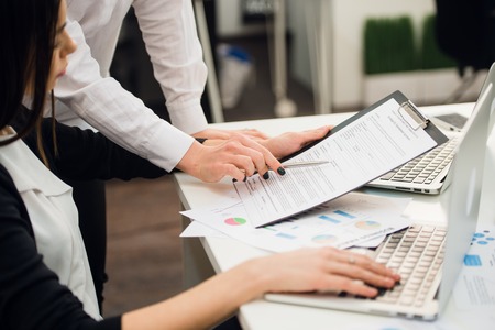 Business team analyzing income charts and graphs with modern laptop computer and using smart phone. Top view close up. Business analysis and strategy concept.の写真素材
