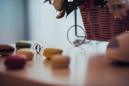 wedding rings on table with bouquet and macaroonsの写真素材