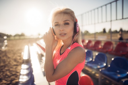 Young beautiful woman with headphones posing over beach volley seats.の写真素材