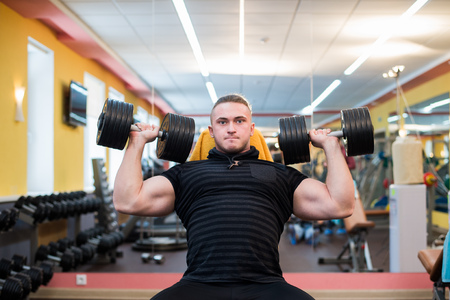 Athletic man is holding the barbell over the head at the gymの写真素材