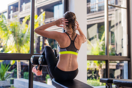 portrait of an athletic woman doing exercising abdominals work-out lying in gym at luxury hotel at...