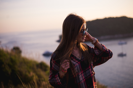 Young stylish hipster girl enjoy sunset on viewpoint. Travel woman with backpackの写真素材