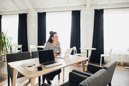 Young attractive woman looking away thoughtfully with her laptop opened.の写真素材