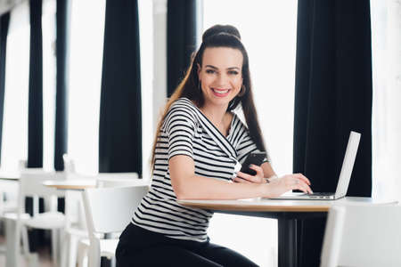 Picture of happy smiling woman using laptop in a cafe and looking at the camera.の写真素材