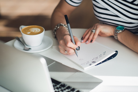 Close up portrait of a womans hands writing a letter.
