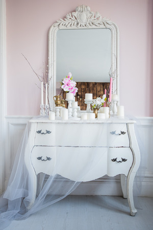 Shabby chic home design. Beautiful decoration table with a candles, flowers in front of a mirrorの写真素材