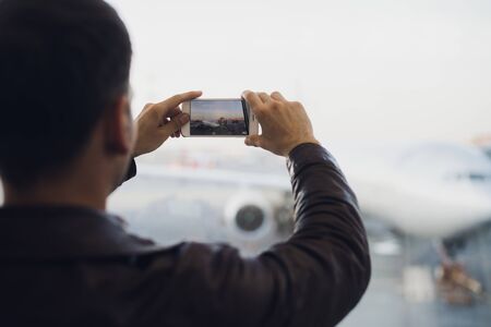 Man hand take picture of airplane using cellphone. Tourism concept photoの写真素材